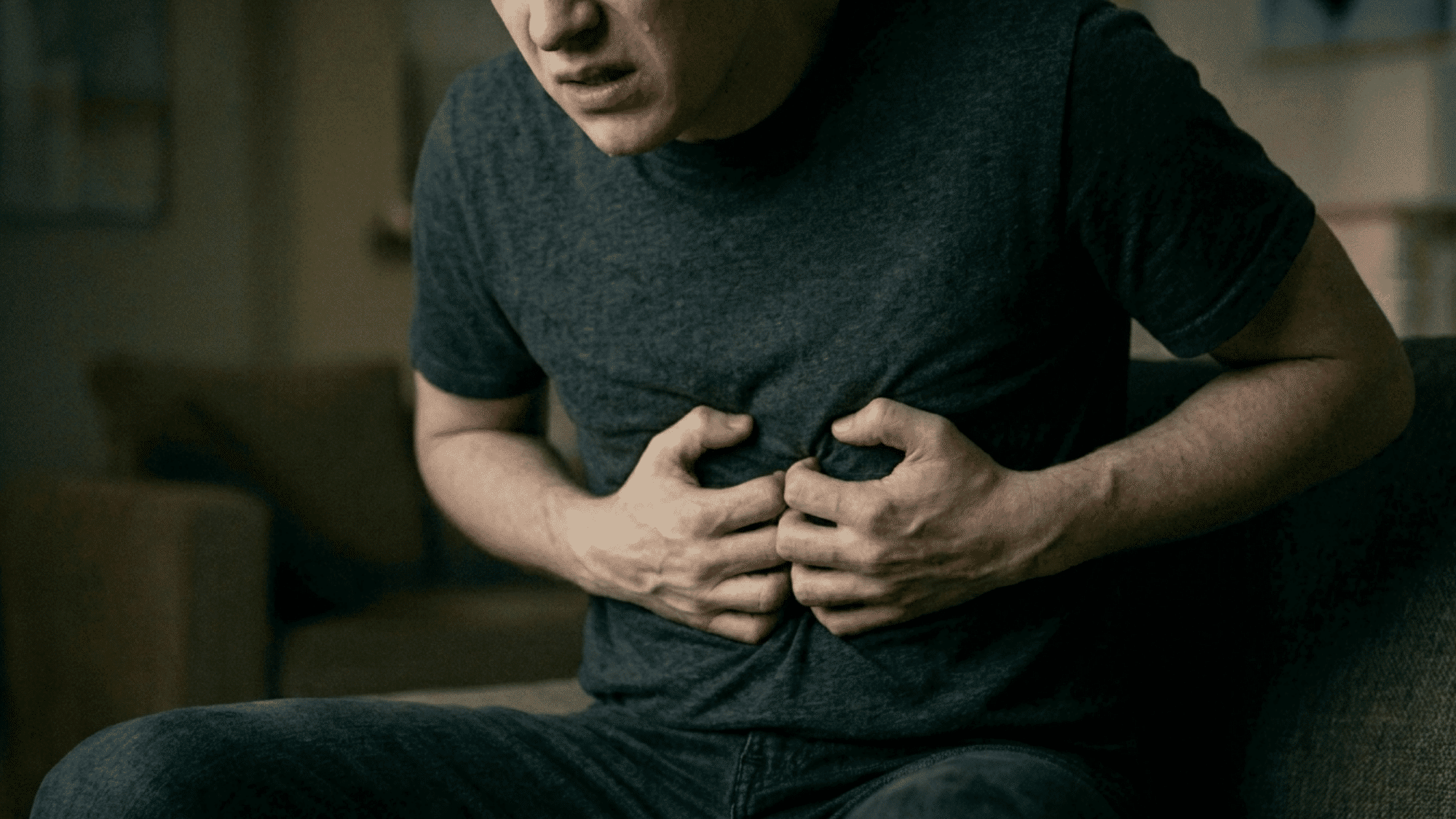 close-up of man clutching stomach in pain and nausea showing symptoms of anxiety and digestive distress