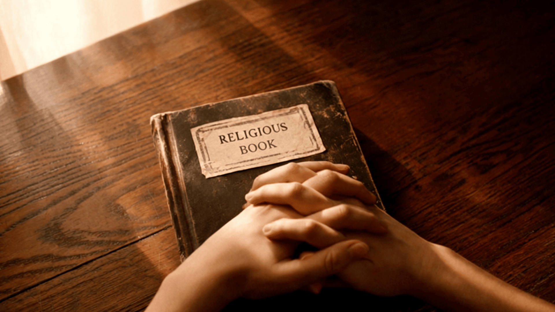 hands clasped in prayer over a worn religious book on a wooden table with warm sunlight streaming through window