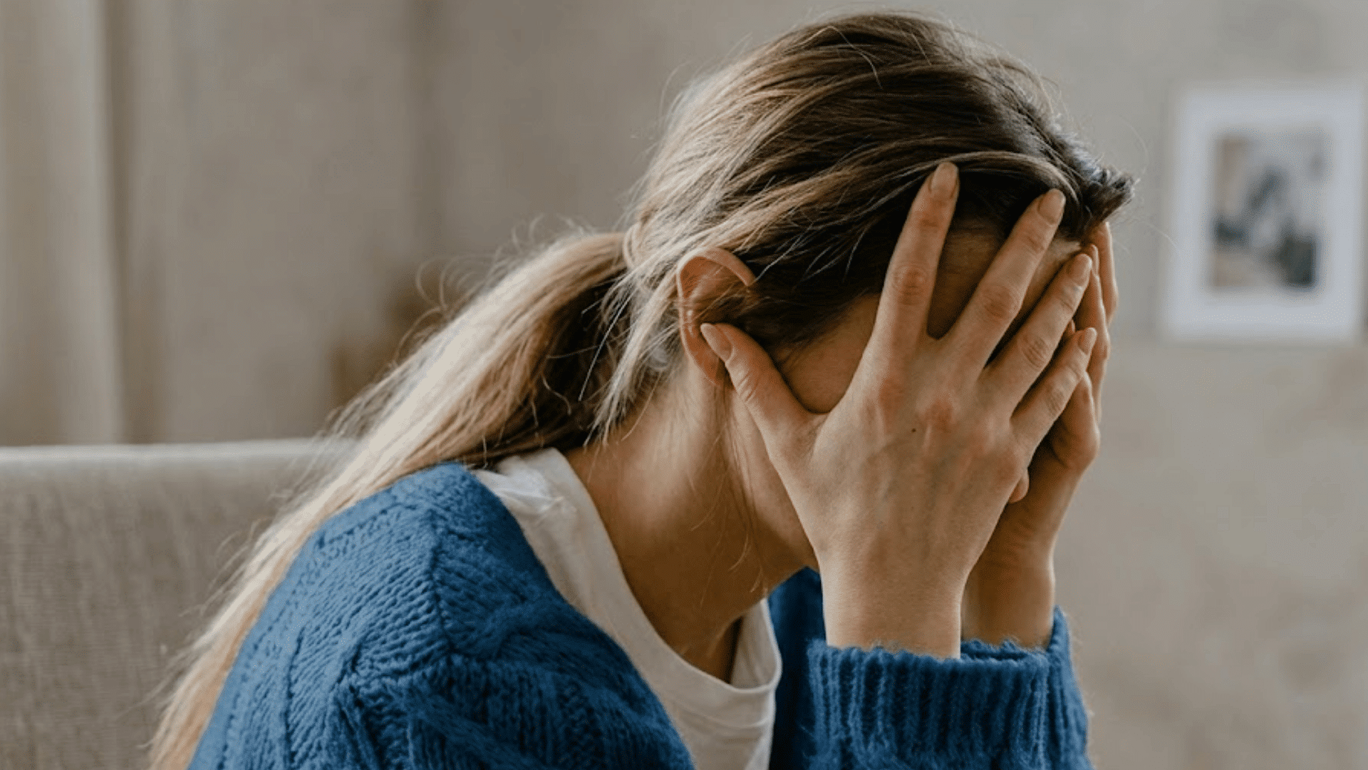 woman sitting with hands covering face showing stress and emotional overwhelm from self criticism