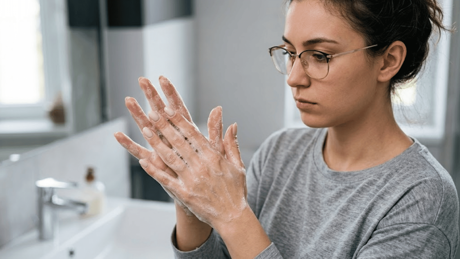 woman washing her hands with soap at a sink, showing repetitive handwashing linked with contamination ocd