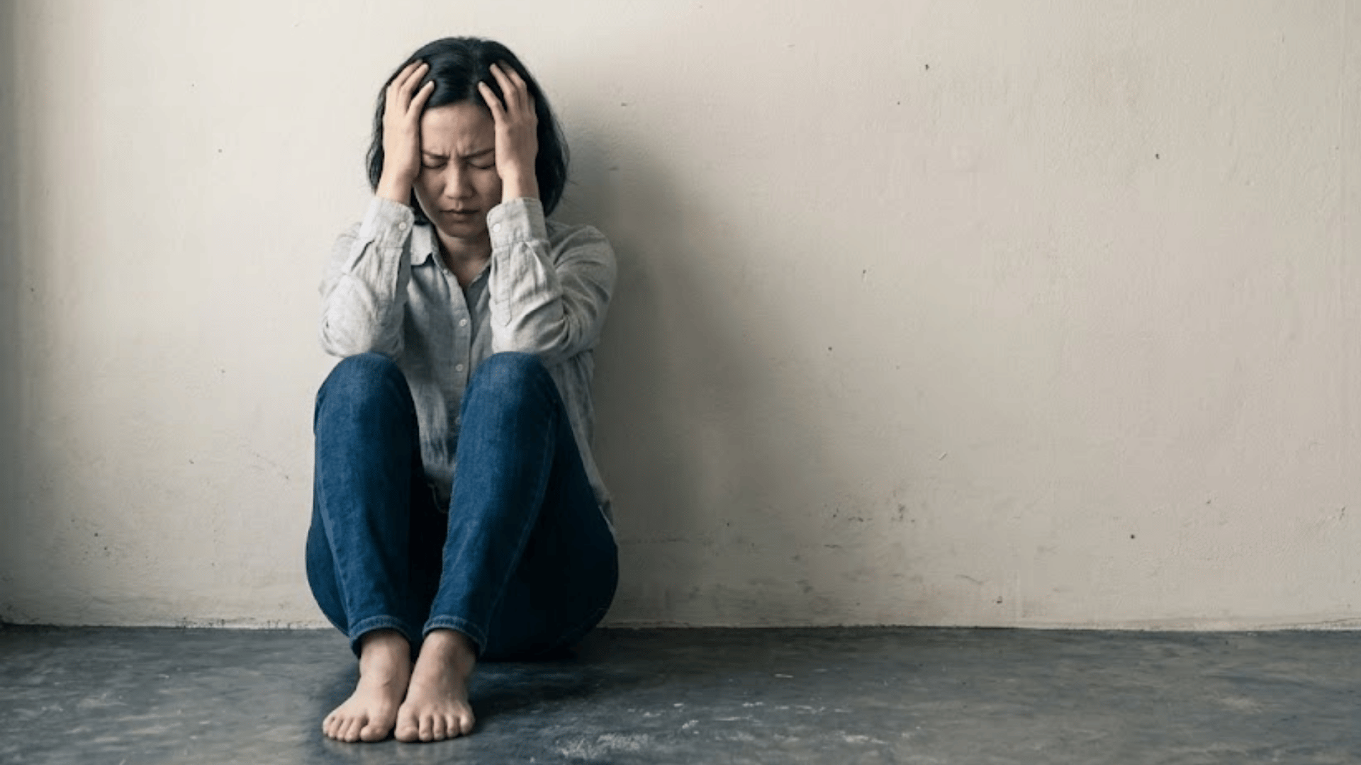 woman sitting alone with hands on head showing emotional distress and signs of panic or anxiety symptoms